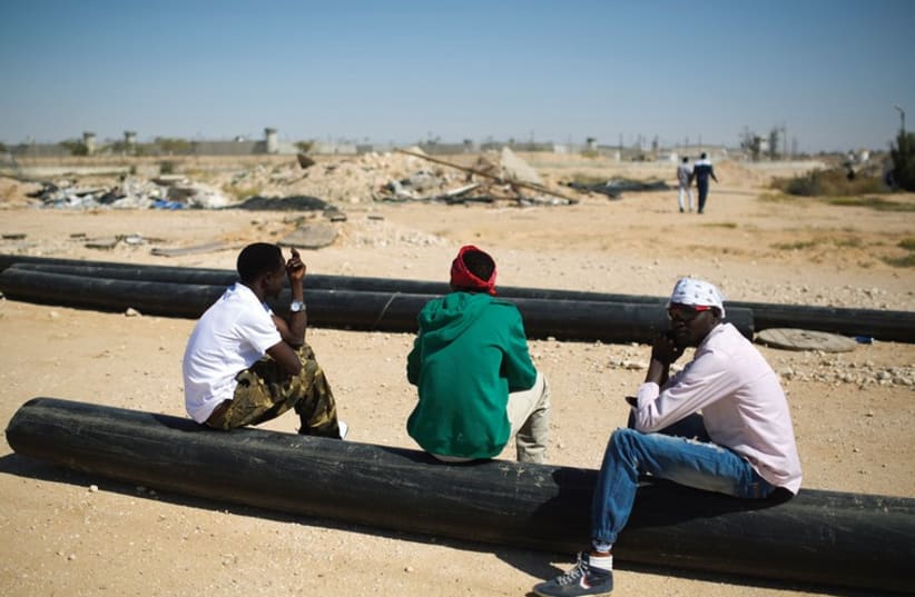 AFRICAN MIGRANTS sit on pipes outside Holot, a detention centre in Israel’s southern Negev desert. (photo credit: REUTERS)