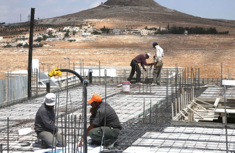Arab construction workers atop a building in the Tekoa settlement. (photo credit: REUTERS)