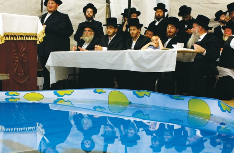 Men pray next to a plastic pool containing fish as they perform the ‘Tashlich’ ritual in Bnei Brak, in this photo from 2013, ahead of Yom Kippur. (photo credit: REUTERS)