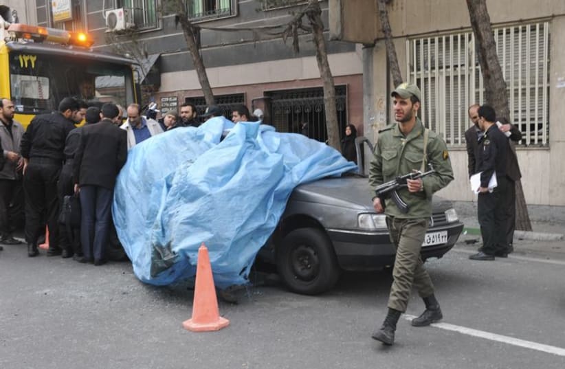 A policeman walks past the car belonging to Iranian nuclear scientist Mostafa Ahmadi-Roshan at a blast site outside a university in northern Tehran January 11, 2012.  (photo credit: REUTERS)