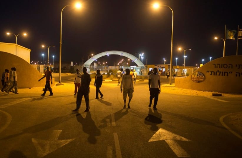 African migrants walk in front of the entrance to Holot open detention center in the Negev  (photo credit: REUTERS)