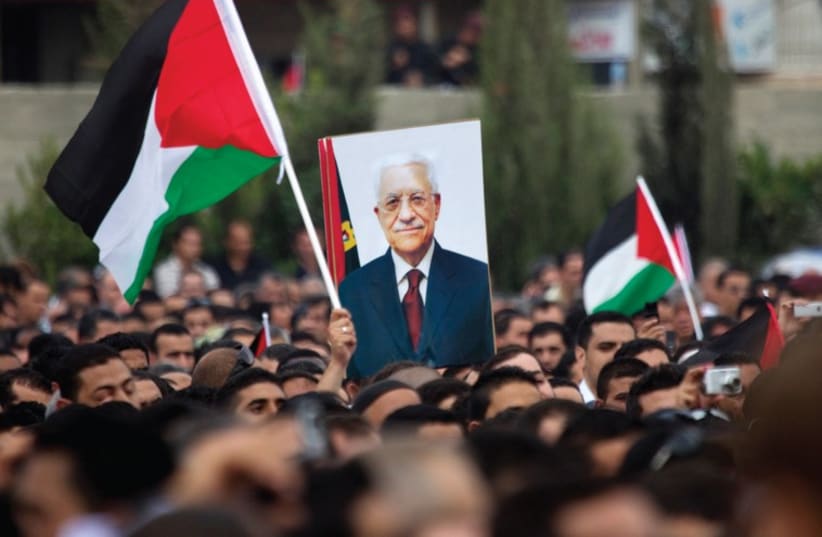 Palestinians marching with a poster of Mahmoud Abbas in Ramallah. (photo credit: REUTERS)
