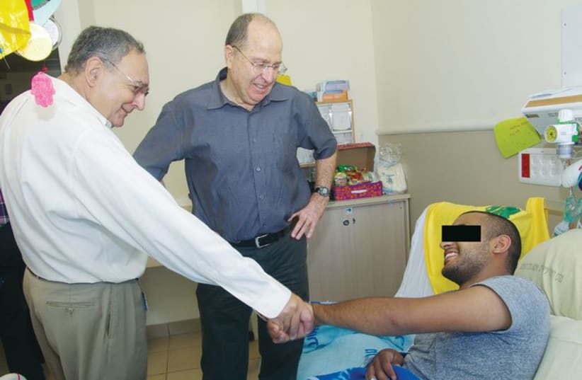 Defense minister Moshe Ya’alon and Prof. Zeev Rotstein visit a wounded soldier at Sheba. (photo credit: YAKOV LEVIT AND ILANA YAACOV FOR SHEBA MEDICAL CENTER)