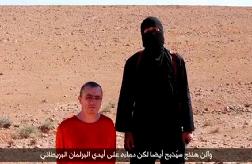A masked man stands next to a kneeling man identified as British citizen Alan Henning (L) in this still image taken from video released by Islamic State (photo credit: REUTERS)