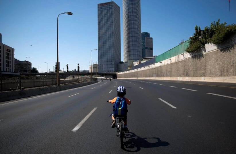 An Israeli boy rides his bike on an empty motorway during Yom Kippur in Tel Aviv (photo credit: REUTERS)