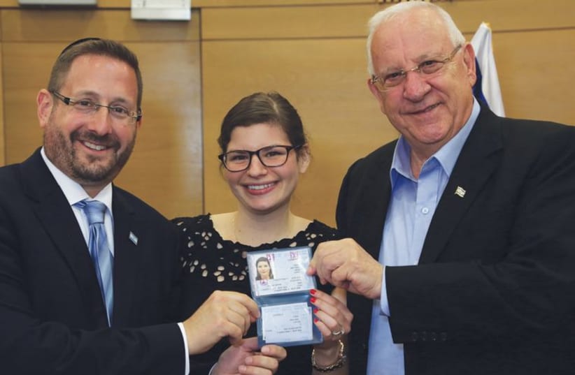 Dov Lipman and President Reuven Rivlin present a ID card to a new immigrant to Israel in July (photo credit: SASSON TIRAM)