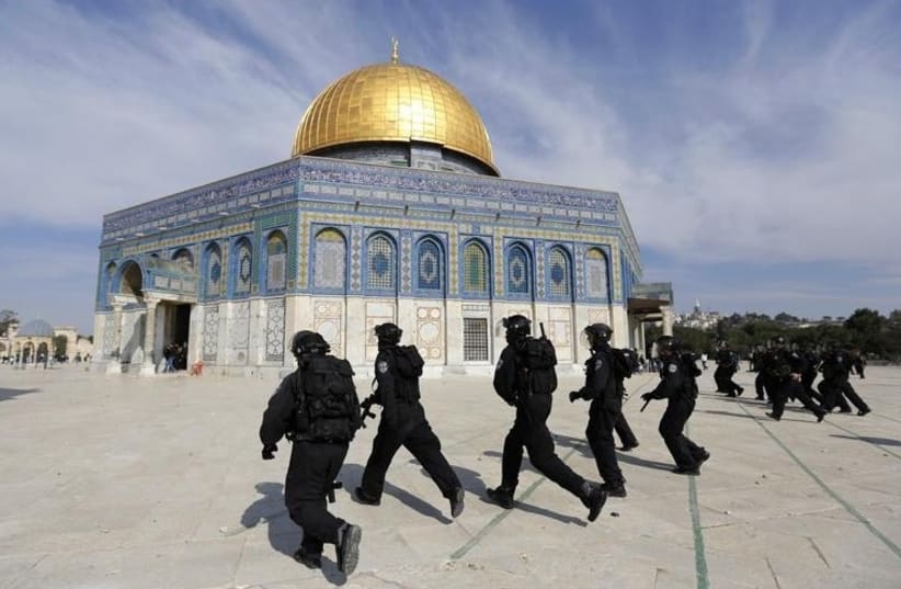 Police officers run in front of the Dome of the Rock during clashes with stone-throwing Palestinians. [File] (photo credit: REUTERS)