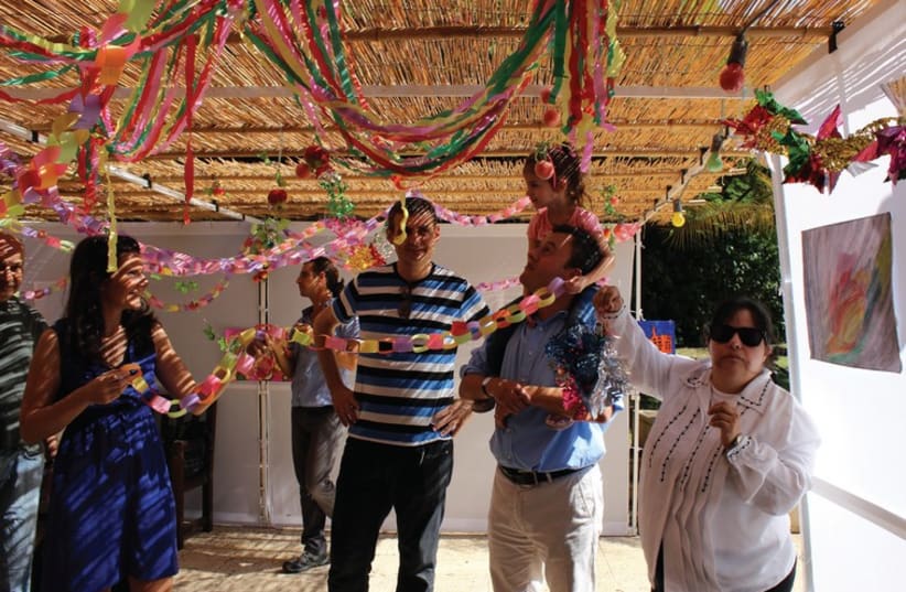Ambassador Matthew Gould, his wife Celia and their daughters, with young people from AKIM Givatayim who came to help decorate their succa. (photo credit: COURTESY BRITISH EMBASSY)