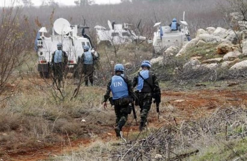 UNIFIL soldiers inspect remains of a shell launched from Lebanon into Israel (photo credit: REUTERS)