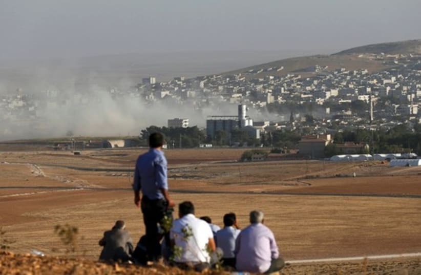 Turkish Kurds look towards the Syrian Kurdish town of Kobani from the top of a hill close to the border line between Turkey and Syria near Mursitpinar bordergate (photo credit: REUTERS)