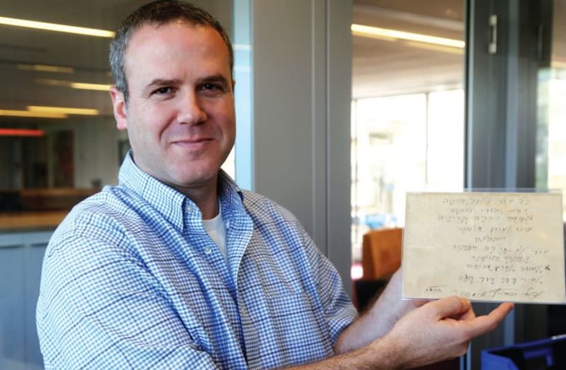 Dr. Aviad Stollman holds one of the National Library’s irreplaceable and ancient manuscripts. (photo credit: MARC ISRAEL SELLEM/THE JERUSALEM POST)