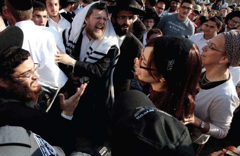 (Left) Male haredi worshipers heckle members of Women of the Wall during a Rosh Hodesh service next to the Western Wall Plaza in July 2013. (photo credit: AMMAR AWAD / REUTERS)
