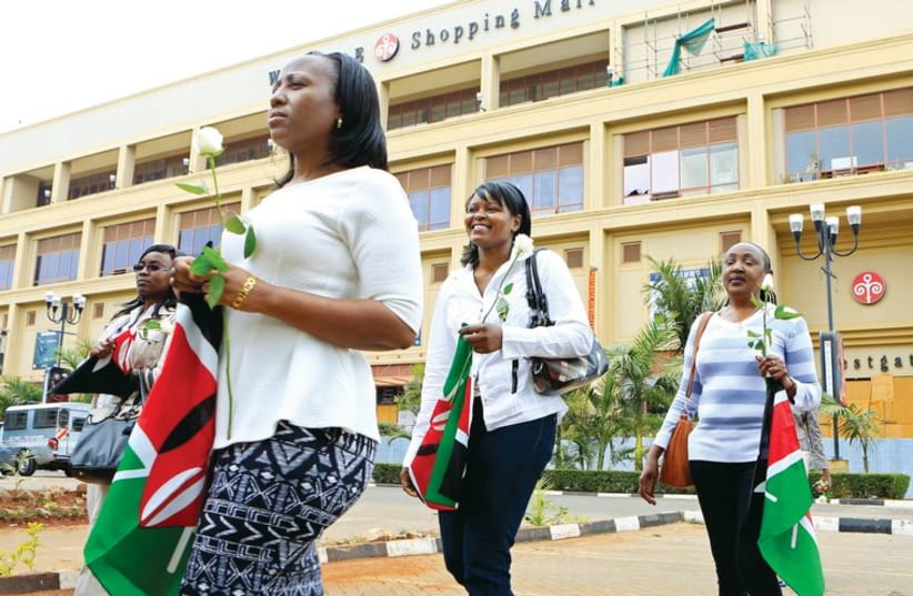 Survivors and relatives of victims carry Kenyan national flags as they attend the first anniversary memorial service of the Westgate shopping mall terrorist attack (photo credit: REUTERS)