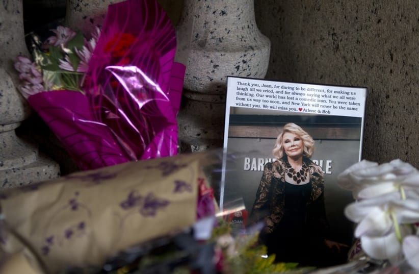 Flowers and a photo left in tribute as part of a makeshift memorial, on the steps in front of Joan Rivers' former residence in Manhattan (photo credit: REUTERS)