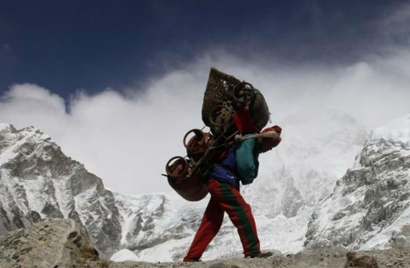 A Nepalese porter walks with his load from Everest base camp in Nepal (photo credit: REUTERS)
