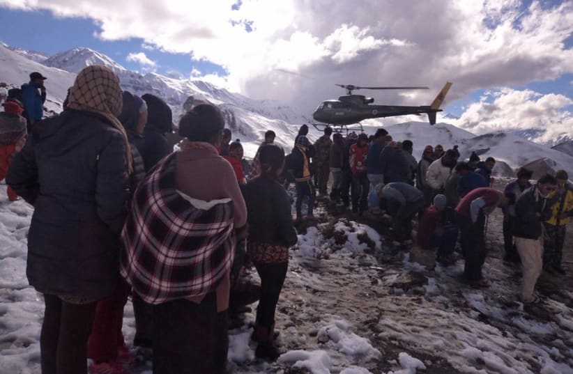 People gather near a helicopter belonging to Nepal Army used to rescue avalanche victims at Thorang-La in Annapurna Region (photo credit: REUTERS)