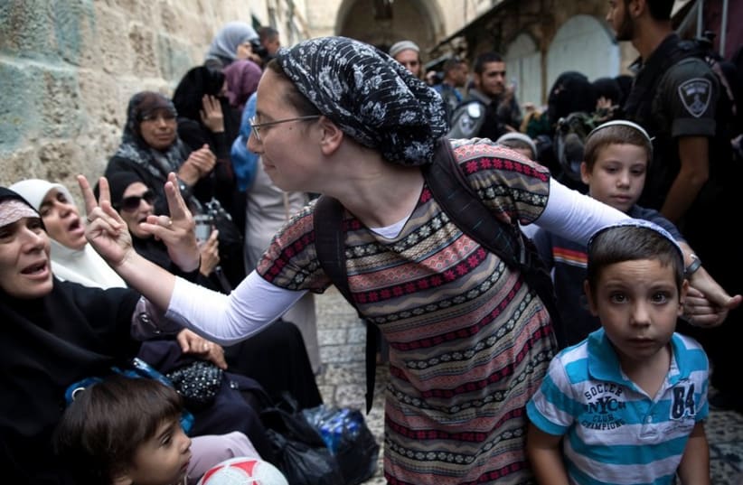 An Israeli woman (C) and a Palestinian woman gesture at one another during a protest by Palestinian women against Jewish visitors to the Temple Mount in Jerusalem's Old City (photo credit: REUTERS)