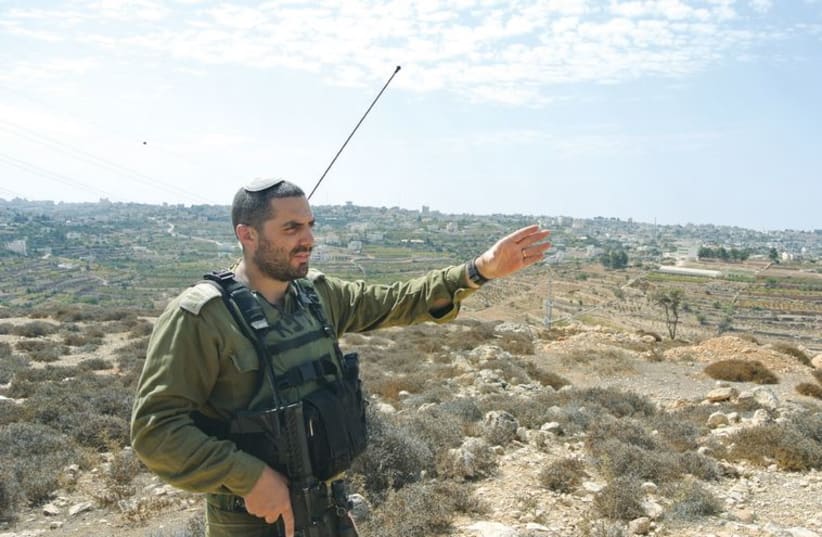 Capt. Eitan Dana-Picard of the Etzion Brigade gestures at an overlook of the town of Halhoul. (photo credit: SETH J. FRANTZMAN)