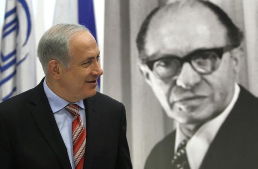 Prime Minister Benjamin Netanyahu walks in front of a poster of the late Prime Minister Menachem Begin upon his arrival at the Likud party meeting at the Menachem Begin Heritage Center in Jerusalem (photo credit: REUTERS)
