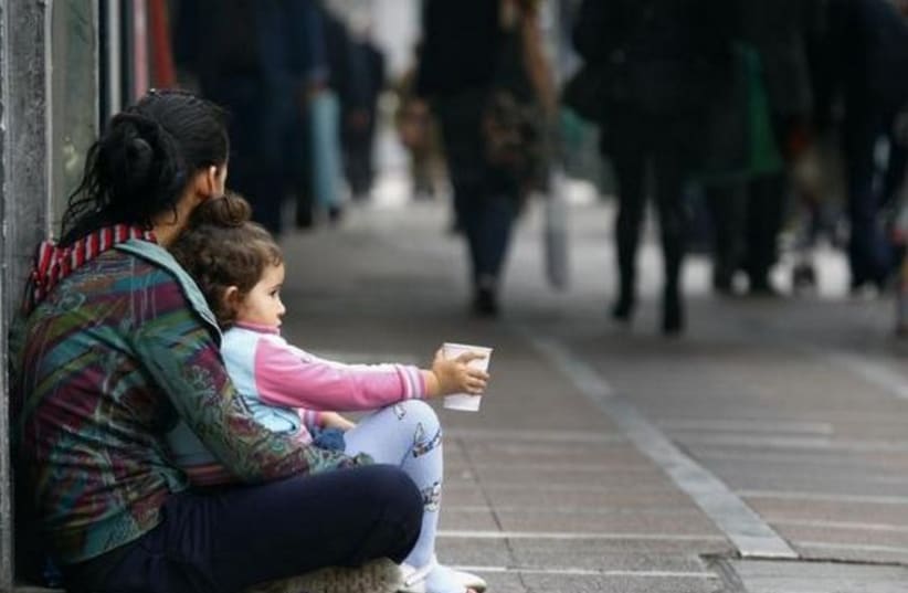 A beggar is seen with her child in central Athens (photo credit: REUTERS)