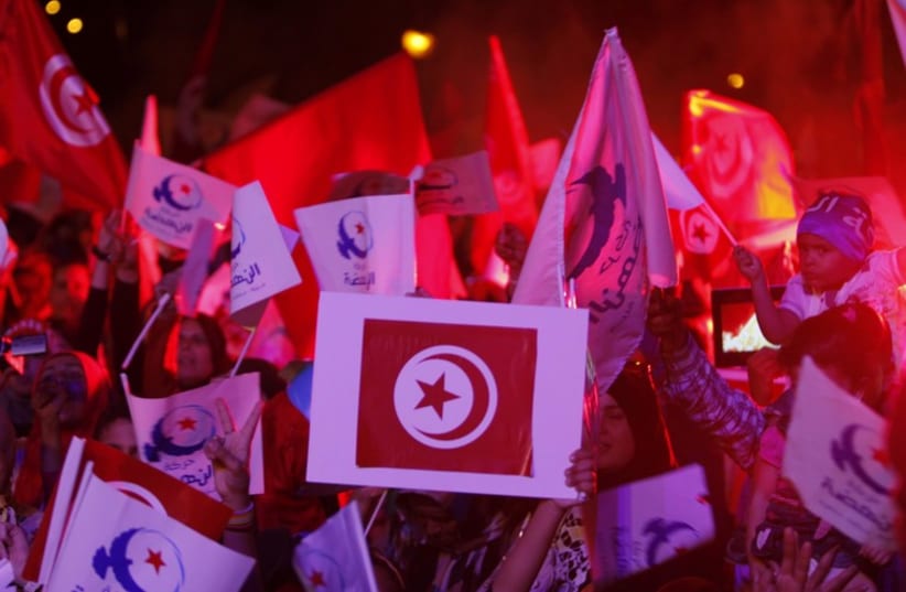 Supporters of the Islamist Ennahda movement wave party flags during a campaign event in Tunis (photo credit: REUTERS)