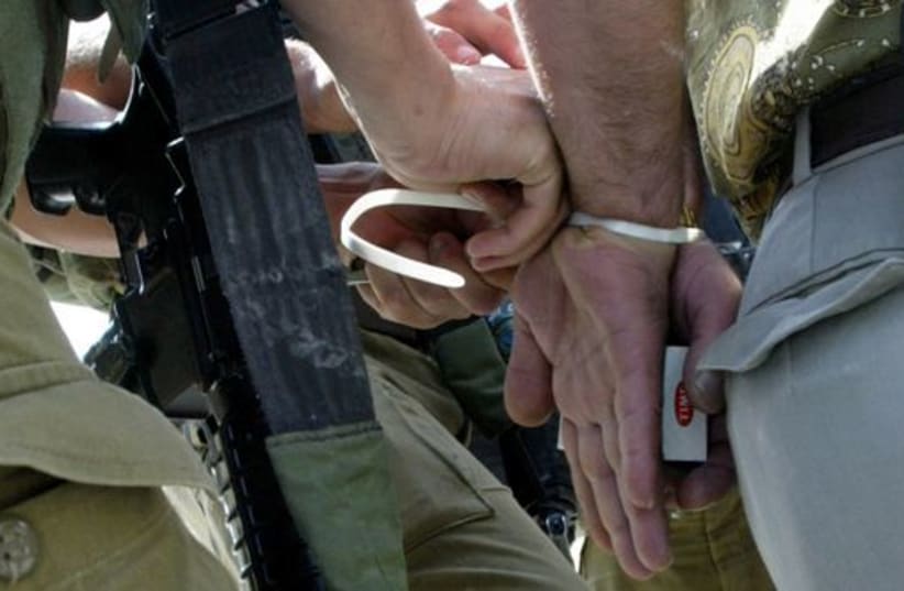 IDF soldier handcuffs a man (photo credit: REUTERS)
