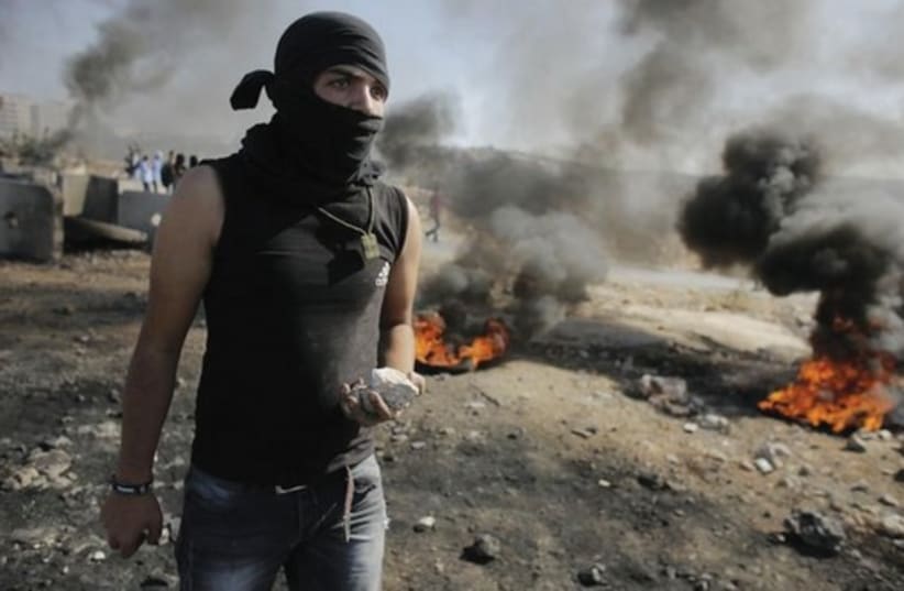 Youth holds stone as Palestinians clash with IDF in the West Bank (photo credit: REUTERS)