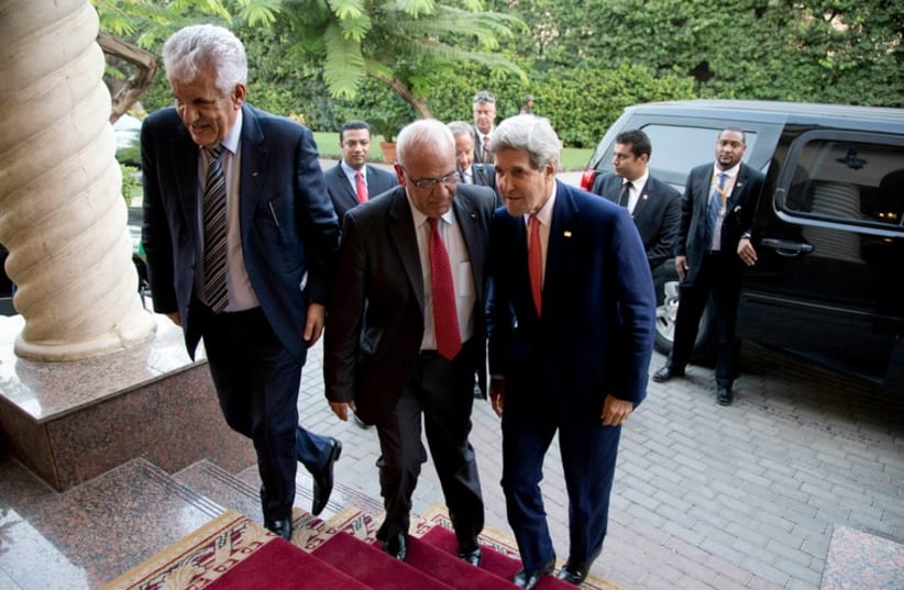 US Secretary of State John Kerry is greeted by Palestinian negotiator Saeb Erakat as he arrives in Cairo October 12 (photo credit: REUTERS)