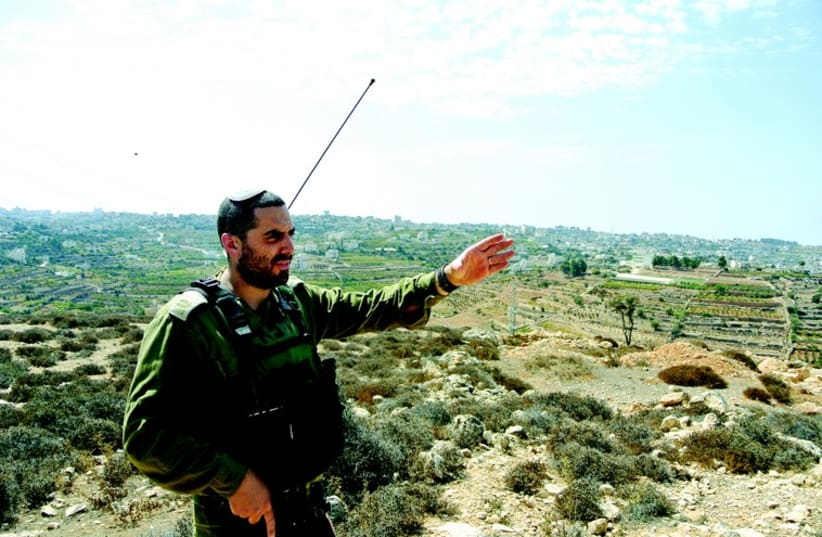 Le capitaine Eitan Dana-Picard indique un point en en surplomb sur la ville de Halhoul. Les corps des adolescents israéliens enlevés ont été trouvés juste au-delà de la colline en terrasses (photo credit: SETH J. FRANTZMAN)