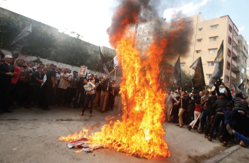 Palestinians burn US and Israeli flags during a demonstration in east Jerusalem last week. (photo credit: REUTERS)