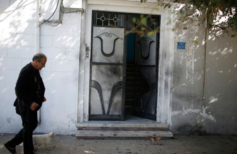 A man walks past a damaged door of a Fatah official's home after an explosion in Gaza City November 7, 2014 (photo credit: REUTERS)