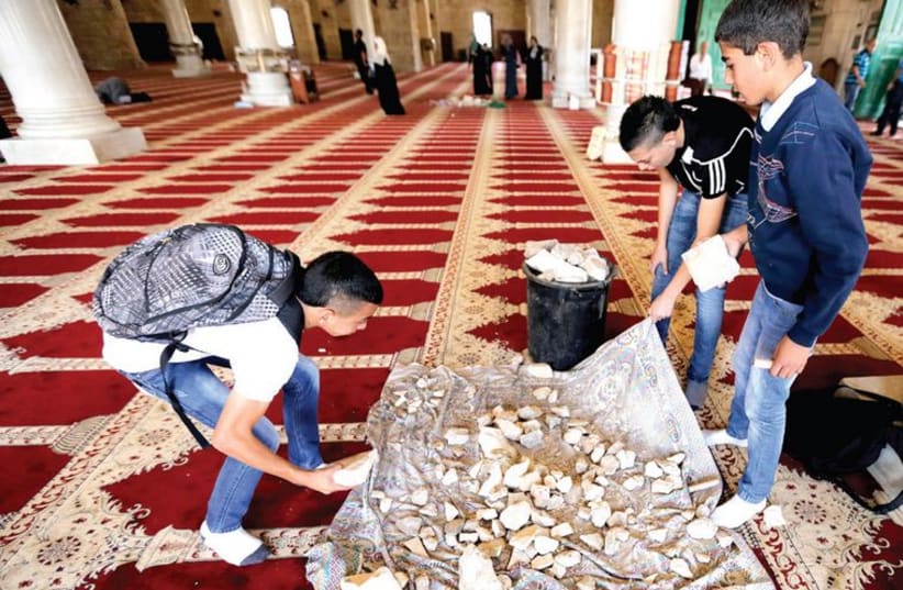 Palestinian youth inside the Al-Aqsa mosque in Jerusalem’s Old City gather stones that were used during clashes with police (photo credit: AMMAR AWAD / REUTERS)