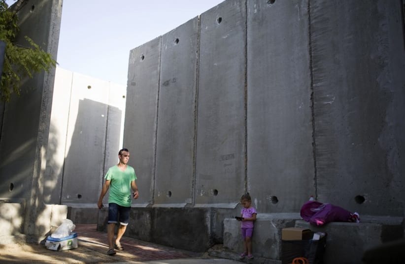 A resident of Nahal Oz walks next to a concrete wall to protect the local kindergarten, just outside the northern Gaza Strip  (photo credit: REUTERS)