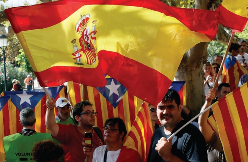 PEOPLE WAVE Spanish and Catalan flags in Barcelona in September (photo credit: REUTERS)