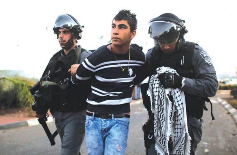 Police detain an Arab youth during clashes at the entrance to the town of Kfar Kanna, on November 8, (photo credit: REUTERS)