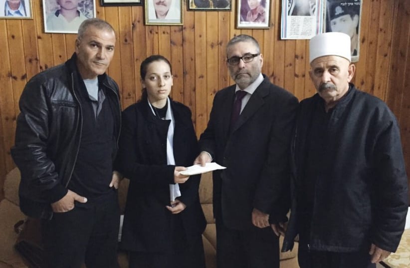 Attorney Mordechai Tzivin (second right) presents $5,000 on Sunday to Rimal Saif, widow of policeman Zidan Saif, who died trying to stop the Har Nof terrorist attack last week. Flanking them are her father and father-in-law (photo credit: MORDECHAI TZIVIN)