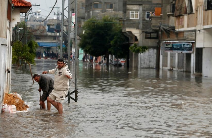 Palestinians place sandbags as they try to prevent rain water from flooding their house following heavy rain in Gaza City November 27 (photo credit: REUTERS)