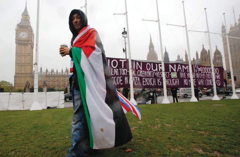 A Palestinian supporter wears Palestinian and Union Jack flags outside the Parliament in London during October's vote on recognizing a state of Palestine (photo credit: REUTERS)