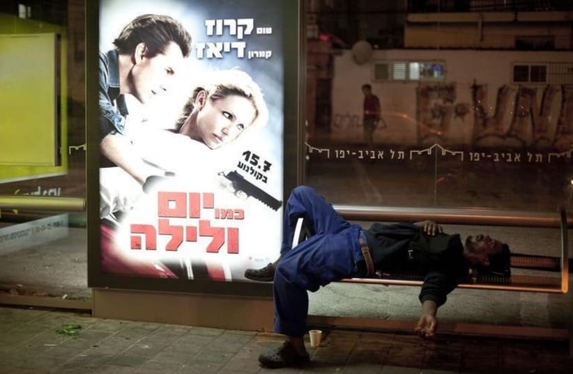 An African migrant worker sleeps on a bench of a bus station in south Tel Aviv (photo credit: REUTERS)