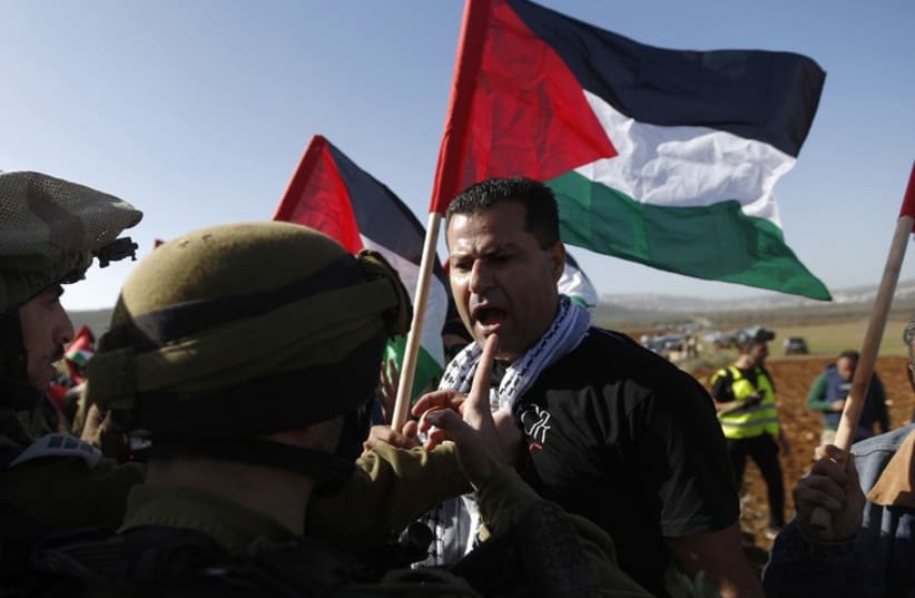 A Palestinian argues with IDF soldiers near Ramallah, December 10, 2014. (photo credit: REUTERS)