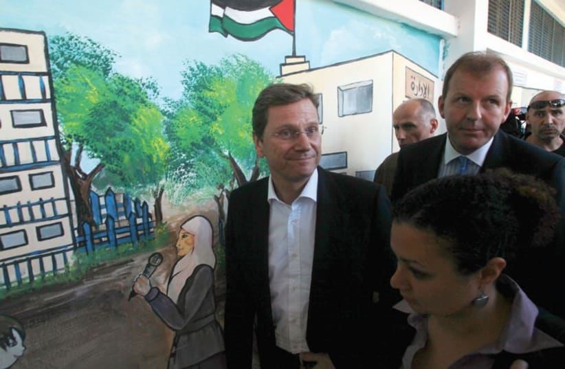 GERMANY’S FOREIGN Minister Guido Westerwelle walks past a mural during a visit to a United Nations Relief and Works Agency (UNRWA) school in Gaza City in November, 2010. (photo credit: REUTERS)