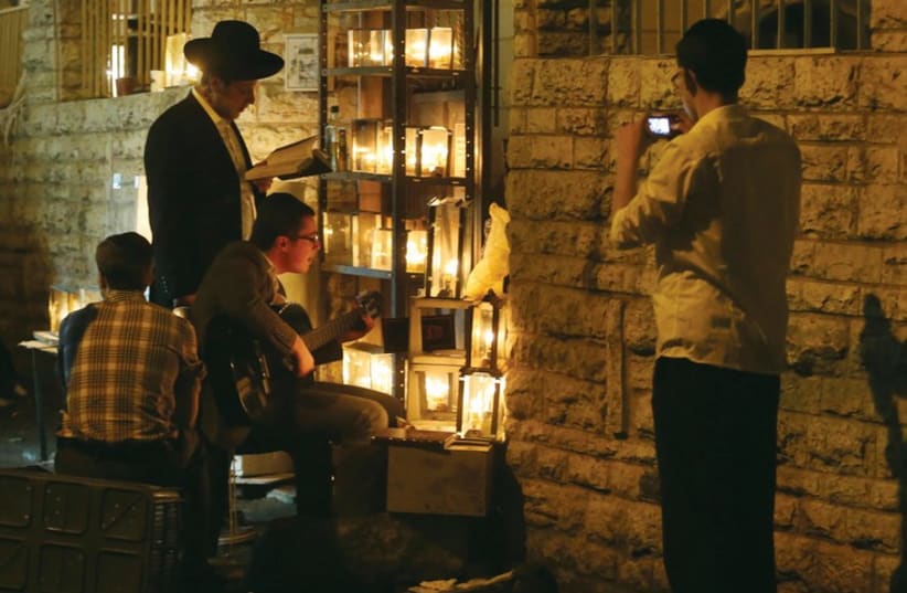 People gather around lit hanukkiot in Jerusalem’s Mea She’arim neighborhood. (photo credit: MARC ISRAEL SELLEM/THE JERUSALEM POST)