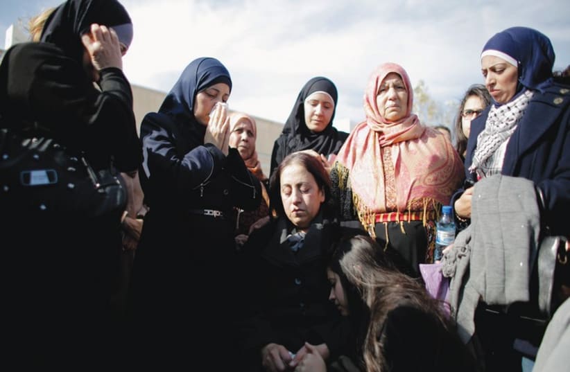 THE WIDOW (center), daughter (kneeling) and other relatives of of PA official Ziad Abu Ein attend his funeral in Ramallah (photo credit: REUTERS)