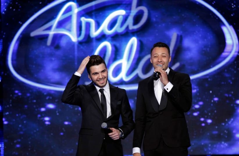 Syrian singer Hazim Sharif (L), winner of Arab idol season 3, stands beside a presenter during the finale in Zouk Mosbeh area, north of Beirut December 13, 2014.  (photo credit: REUTERS)