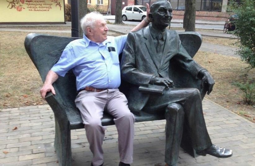Israel Zamir poses with a sculpture of his father in Bilgoray, Poland. (photo credit: COURTESY MEIRAV HEN)