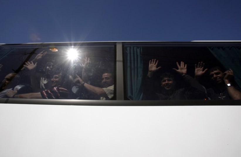 Palestinian prisoners who were released from Israeli prisons as part of a prisoners exchange deal between Israel and Hamas wave from a bus  (photo credit: REUTERS)