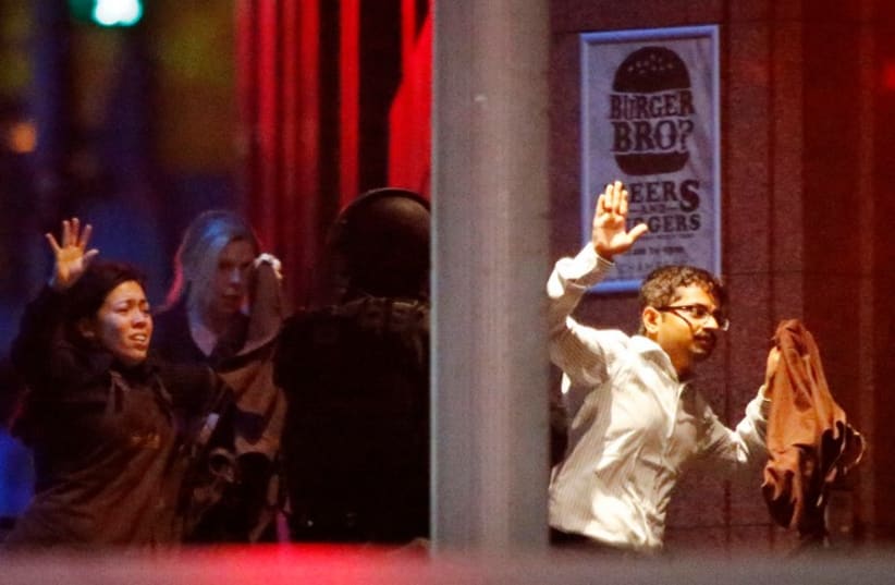 Hostages run past a police officer (C) near Lindt Cafe in Martin Place in central Sydney December 16, 2014.  (photo credit: REUTERS)