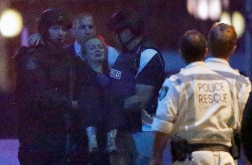 Police rescue personnel carry an injured woman from the Lindt cafe, where hostages are being held, at Martin Place in central Sydney. (photo credit: REUTERS)
