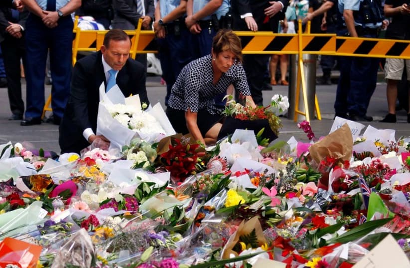Australian Prime Minister Tony Abbott and his wife Margie place flowers at the makeshift memorial for the hostage victims of the Sydney cafe siege (photo credit: REUTERS)