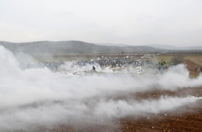 Protesters run away from tear gas fired by Israeli troops during clashes following a demonstration against Israeli settlements near Ramallah (photo credit: REUTERS)